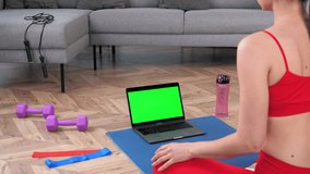 Green screen mock up chroma key monitor laptop: Fit fitness woman in sportswear sits on yoga mat doing warm-up before training workout exercise, online sport lesson course video call webcam computer
