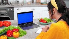 Blue screen mock up chroma key monitor display laptop: Woman housewife in home kitchen tells chef listen teacher shows ingredients for cooking in webcam, study online remote video call chat computer