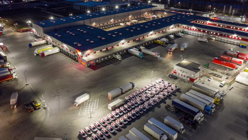 Aerial hyper lapse (motion time lapse) of a logistics park with a loading hub. Semi-trailers trucks stand at warehouse ramps for load and unload goods at night. Royalty-Free Stock Footage #1072321457