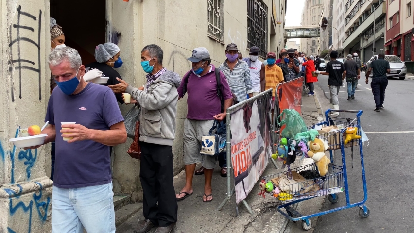 Sao Paulo, SP, Brazil - May 12, 2021: People form a long line to receive food donations for lunch in a downtown street during a severe economic crisis amid the Coronavirus, COVID-19 pandemic.