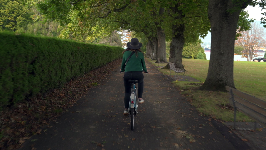 Cool Canadian girl wearing a hat cycling around Stanley Park during fall season in Vancouver, British Columbia, Canada.