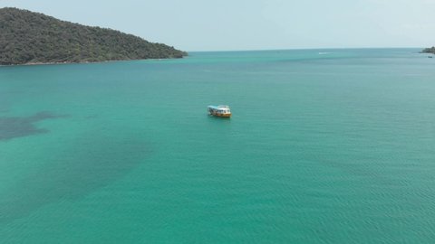 Lone Cambodian Boat in the middle of the turquoise paradisiac sea in M'pai Bay, Koh Rong Sanloem, Cambodia - Aerial Top view Fly-over