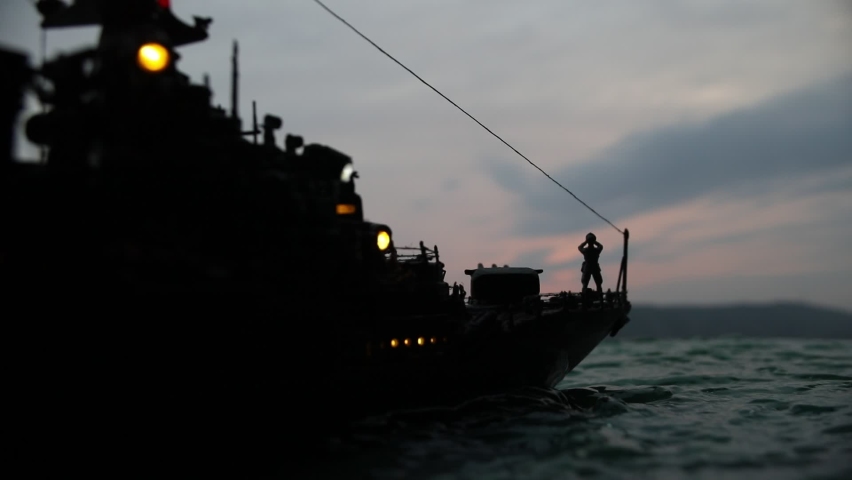 War concept. Night battle scene at sea. Dramatic toned clouds effect. Silhouette of the battle ship at sunset. Miniature creative table decoration. Selective focus