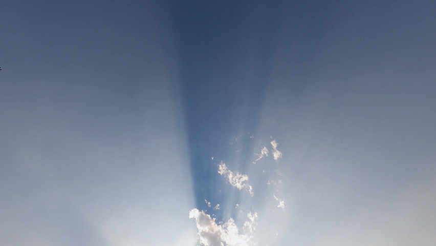 Beautiful sun rays sunbeams shine in wide space of clear blue sky. Heavenly sky in summer day background. Amazing light from heaven in low angle view. Look up to the high blue sky. Sun shine through 