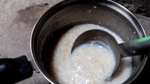 Making porridge in a bowl with spoon in Lockdown. Closeup shot of porridge with big spoon. Porridge of milk wheat and sugar, oats. Delicious porridge breakfast on desk. 