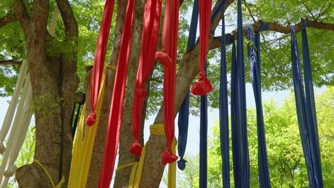 Seonangdang, holy stone cairns or trees dedicated to the patron deity of a village. Multicolored Ribbons with stones Hanging On Branches Of A Tree At Korean Folk Village