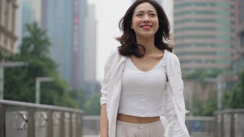 4k slow motion of conficent pretty young asian woman walking in the urban city street with high building in the background at Chengdu China