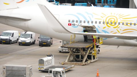 AMSTERDAM, THE NETHERLANDS - JULY 29, 2017: Unload baggage from an airliner. TUI Fly Boeing 767 HB-JJF arrived at the airport, airport staff unload the luggage from the plane, Schiphol Airport