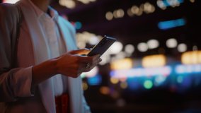 Focus on Female Hand Using Smartphone Walking Through Night City Street Full of Neon Light. Woman Holding Mobile Phone, Posting Social Media, Online Shopping, Texting. Tracking Shot - Powered by Shutterstock - Get 15% off with code: PIKWIZARD15