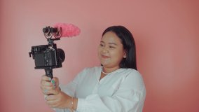Young woman vlogger recording broadcast in slow motion on a pink background