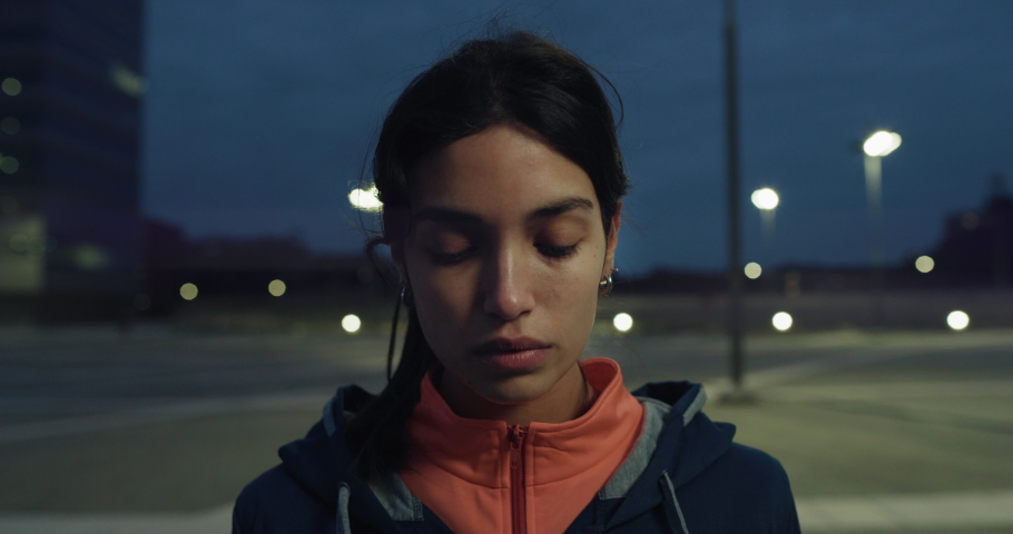 Cinematic close up shot of young arab sportswoman putting on hood and looking in camera before run with dedication in city center at night. Concept of determination, woman power and sport wear. Royalty-Free Stock Footage #1072358186