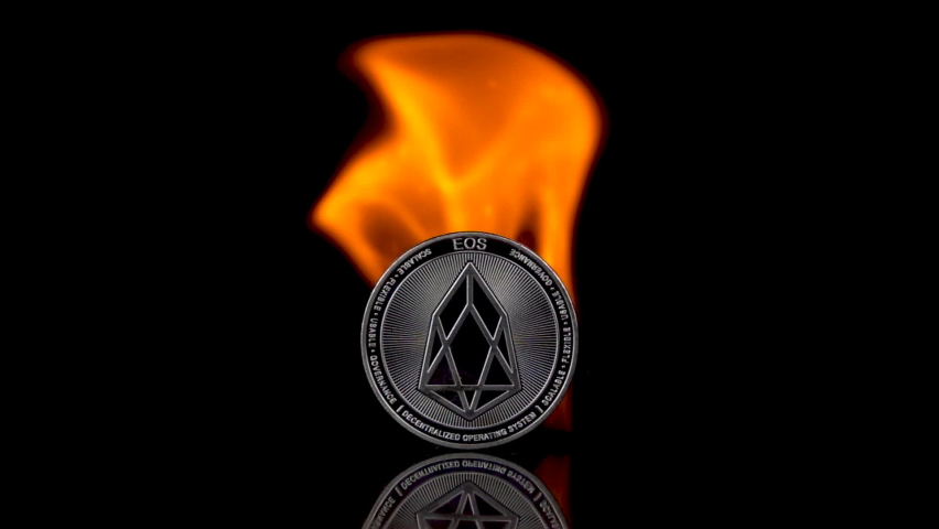 EOS coin catches fire on an isolated black background. Slow motion 250fps.