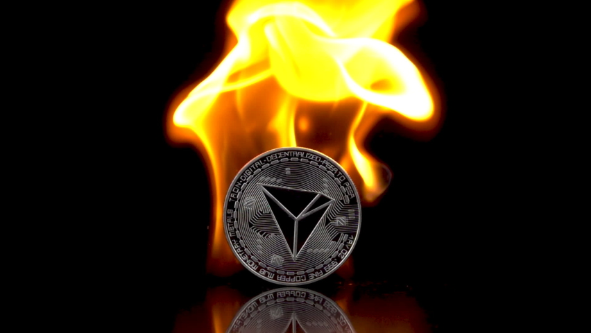 Tron - TRX coin catches fire on an isolated black background. Slow motion 250fps.
