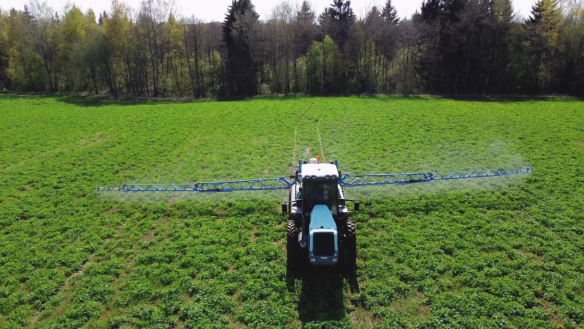 Aerial view of autonomous self-driving tractor with autopilot spraying mineral, nitrogen fertilizer or pesticides on an agricultural field. The agricultural vehicle uses sensors and a GPS signal. Royalty-Free Stock Footage #1072363775