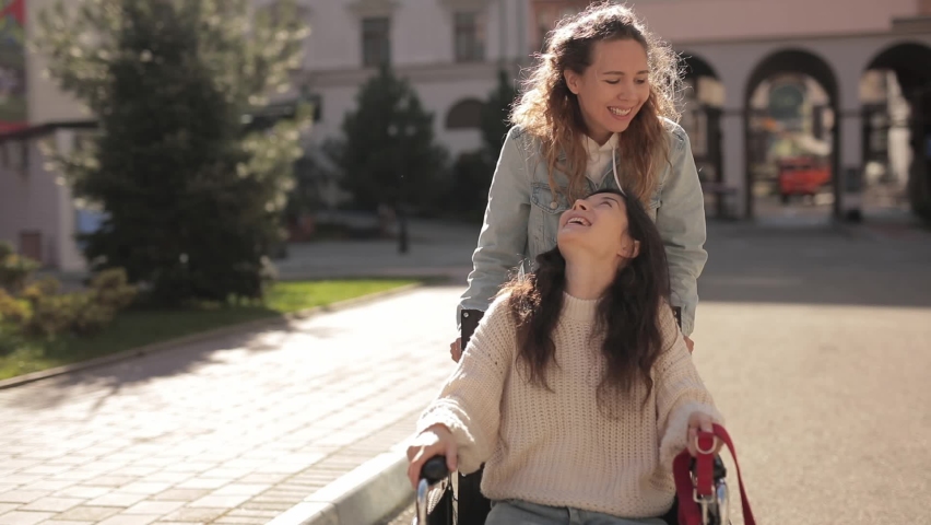 happy and laugh friends. Power of friendship. Pretty disabled invalid asian girl sitting on wheelchair with guide dog while riding on outdoors with her girlfriend. Three happy diverse multiracial Royalty-Free Stock Footage #1072366643