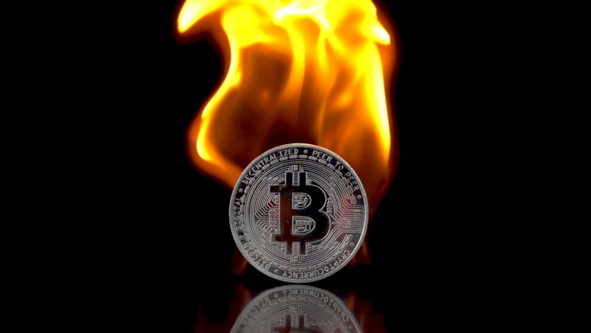 Bitcoin - BTC coin catches fire on an isolated black background. Slow motion 250fps.