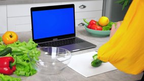 Blue screen mock up chroma key monitor display laptop: Woman housewife in home kitchen greets tells chef slices cucumber on cutting board listen teacher, study online video call chat webcam computer