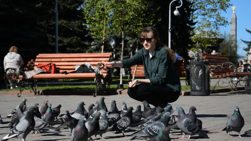 Beautiful young girl student feeding pigeons in the summer