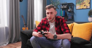 Collage student boy is enjoying video game using controller concentrated on interesting activity in apartment. Teenagers lifestyle and leisure time at home concept.