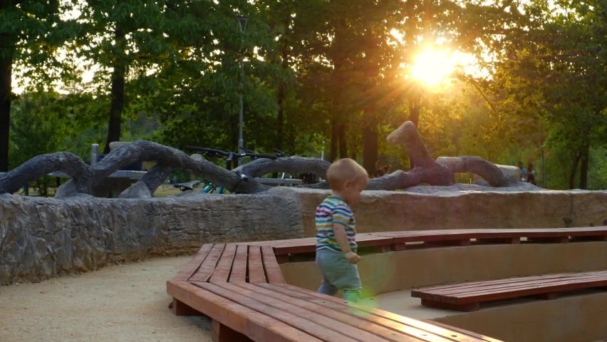 Toddler Cautiously Going Down Stairs at Public Park By Sunset; Baby Boy Exploring the World