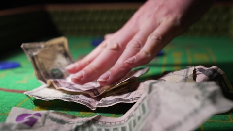 This close up video shows anonymous hands tossing down crumpled cash onto a craps gambling table.