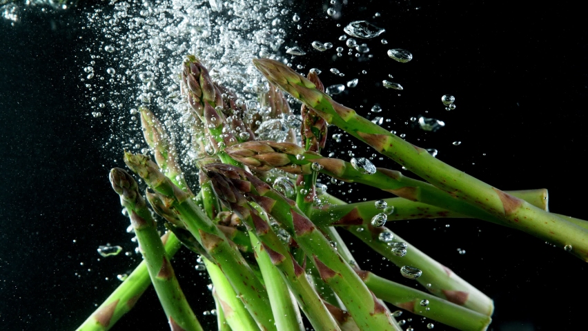 Super slow motion of falling asparagus into water. Black background. - Powered by Shutterstock - Get 15% off with code: PIKWIZARD15