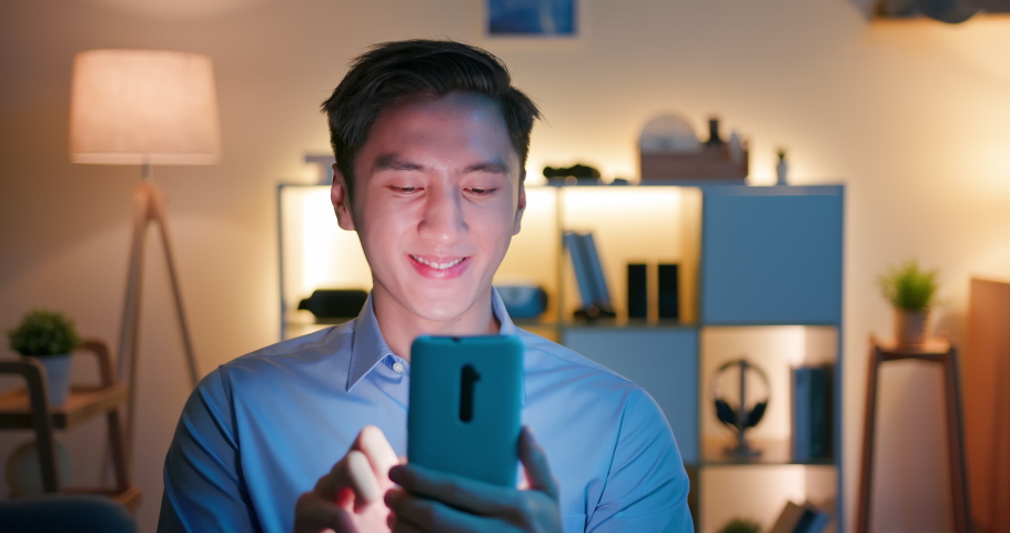 Asian man use smart phone and watches something interesting on social media happily at home in the evening | Shutterstock HD Video #1072384208