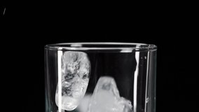 Close-up Slow motion shot of ice cubes falling into a cocktail empty glass isolated on black background. action. Making a cocktail with ice. 100FPS - Powered by Shutterstock - Get 15% off with code: PIKWIZARD15