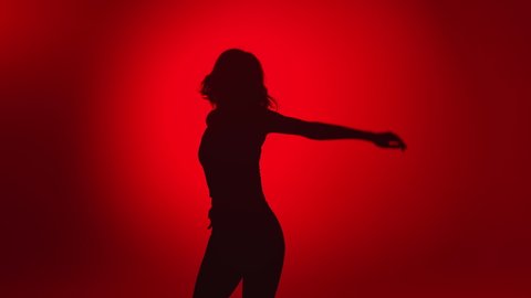 Seductive woman dancer shadow demonstrate dance movement isolated on red gradient studio background. Young flexible lady with perfect body dancing slow motion. Shot with RED camera in 4K