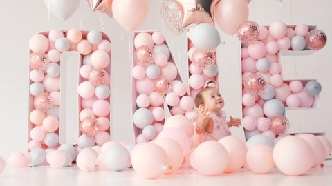 Little cute girl smiling with colorful balloons white and pink in birthday decoration