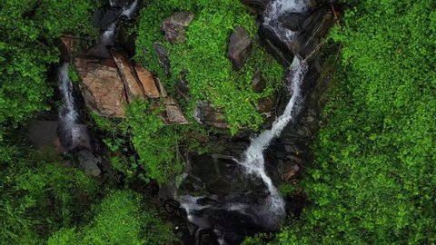 Aerial Drone shot of beautiful waterfall surrounded by green forest. Down to Top, Close to Wide pull out drone shot of waterfall in Sri Lanka. Beautiful greenery drone shot. Dramatic Aerial 4K footage