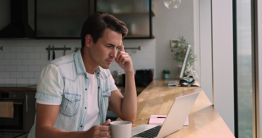 Man sit in kitchen drink morning coffee to perk up working on modern wireless laptop, learn new app, think over response to client, texting message, male freelancer do telework job from home concept Royalty-Free Stock Footage #1072405676