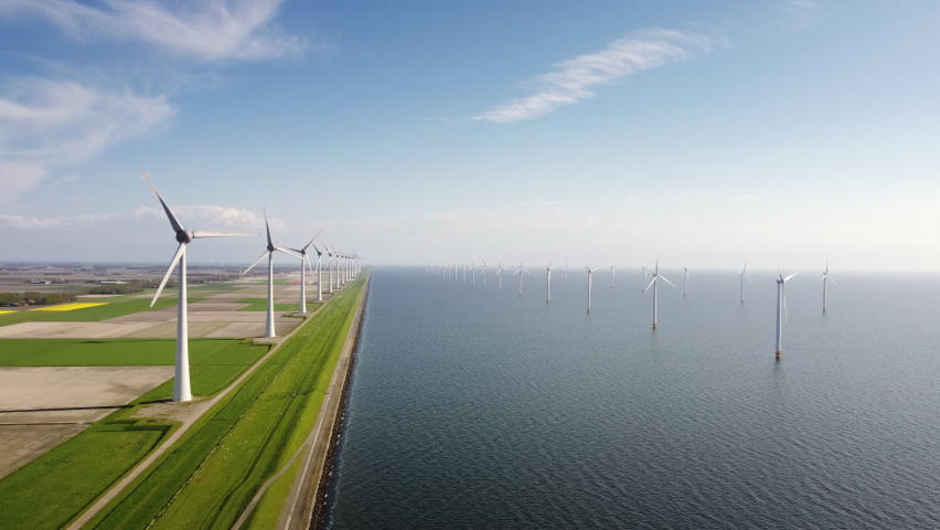 Wind turbines on a levee and off shore wind turbines off the coast of Flevoland in the IJsselmeer in The Netherlands. Aerial view. | Shutterstock HD Video #1072412402
