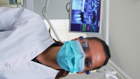 Vertical video: Patient pov in dental chair making performing periodic teeth check in modern stomatological clinic. Dentistry doctor lighting the lamp and examining person wearing protection mask and