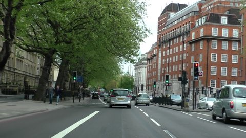 LONDON, ENGLAND, UNITED KINGDOM - CIRCA APRIL, 2017: Car point of view, POV driving Marylebone Road in central London, stopping at traffic lights by Regents Park, near station.