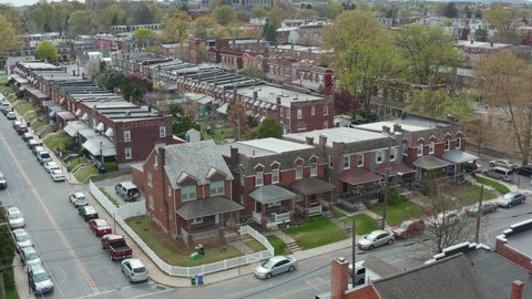 Aerial of brick and brown stone houses in urban city in USA. Establishing shot during spring season, blooming trees.