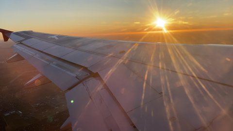 Leaving Saint Petersburg, Russia, seen from airplane window, passenger plane wing at sunset over the city.