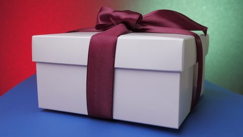 Decorative anniversary present box with purple ribbon and bow on blue table against green and red wall close view. Concept celebration