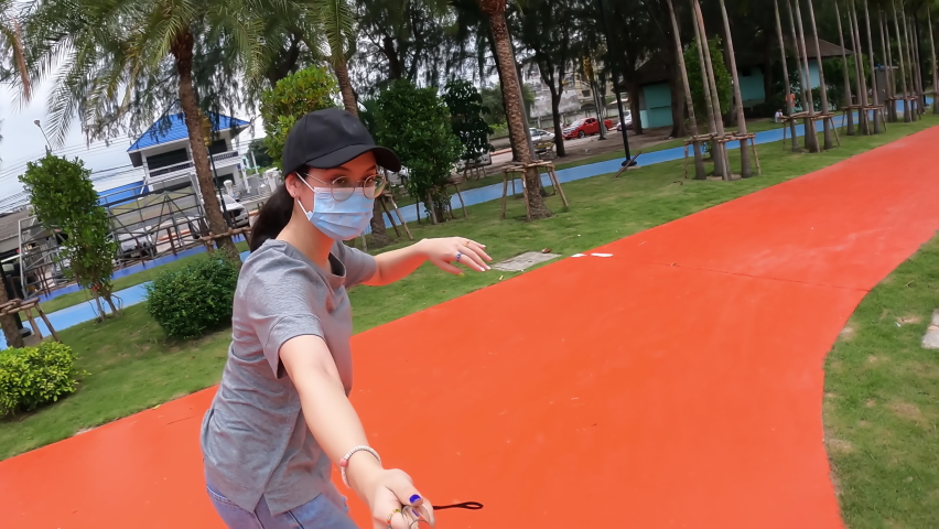Happy Young woman wearing facemask selfie and video record during exercise surfskate at park
