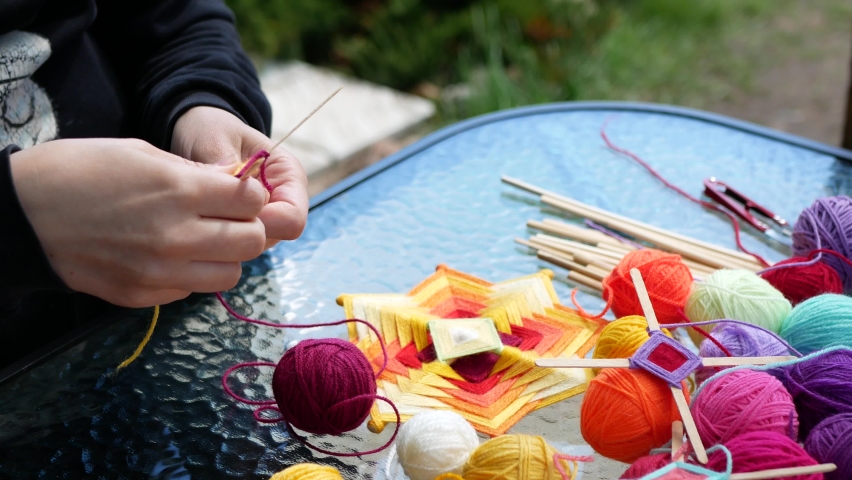 Transforming raw materials into a harmonious mandala. Woman is weaving mandala using wooden sticks and colored yarn. Handcraft process | Shutterstock HD Video #1072441931