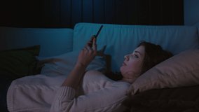 Millennial Woman Holding Cellphone Lying On A Couch, Swiping Photos In Online Dating App. Young girl using mobile application, web surfing, social networks. Virtual relationships, Smartphone Addiction