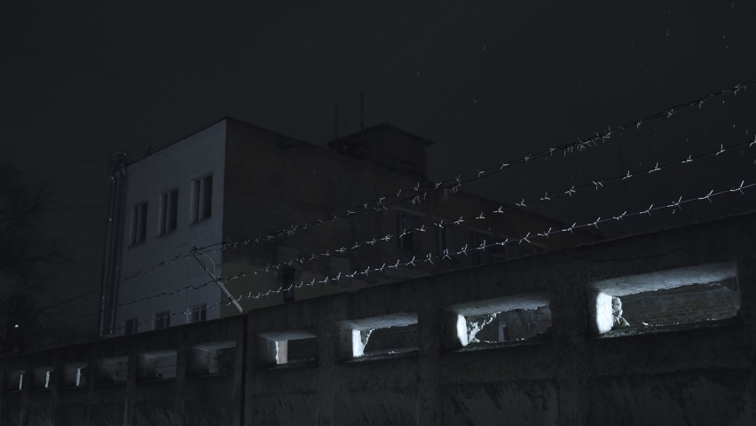 prison barbed wire over concrete fence against cloudy sky at cold dark winter night during snowfall. incarceration, jail, restricted area, closed zone, security concept Royalty-Free Stock Footage #1072455653