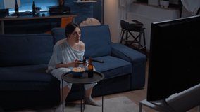 Gamer using joystick playing video games with joystick sitting on couch in living room winning competition. Excited determined woman using controller gamepad keypad playstation gaming and having fun