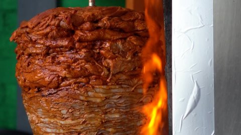 Trompo de pastor, typical mexican food. Close up of trompo al pastor for tacos with the fire lit