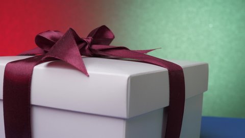 Decorative anniversary present box with purple ribbon and bow on blue table against green and red wall panorama. Concept celebration