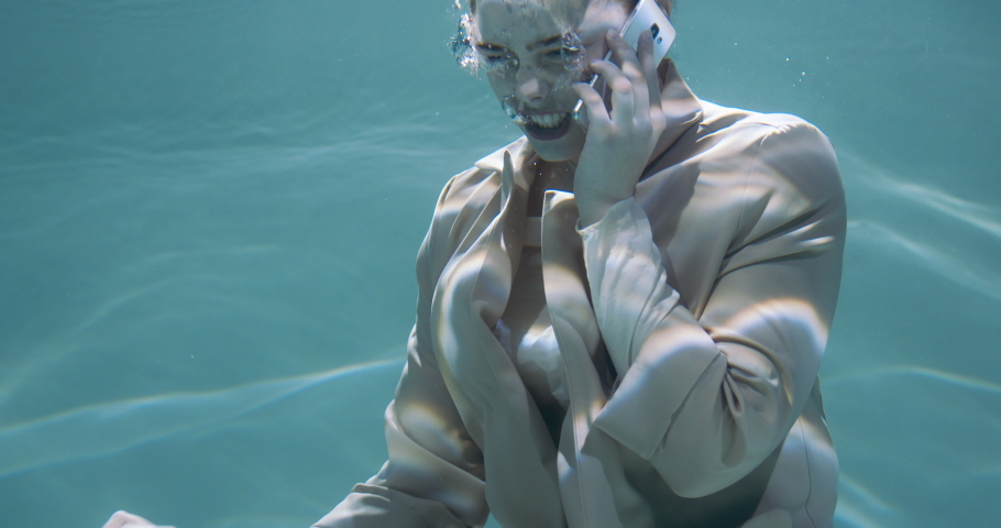 Cinematic under water portrait of angry stressed young redhead business woman shouting talking on phone call slow motion