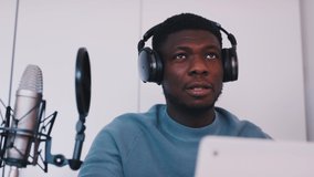 Man wearing headphones taking an online class using a laptop and microphone. Concept of online classes or podcasts. Explaining something using hand gestures. Distance learning. . High quality 4k
