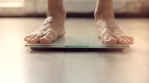 Walking Male Checking BMI Weight Loss. Human Barefoot Measuring Body Fat Overweight. Man On Scales Measure Weight. Guy Legs Step On Bathroom Scale. Diet Man Feet Standing Weighing Scales On Room