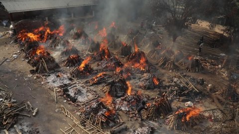 New Delhi, India, May 16, 2021 Relatives pays last respects to those who died from the COVID-19 coronavirus disease as other funeral pyres seen during the mass cremation at Ghazipur crematorium   