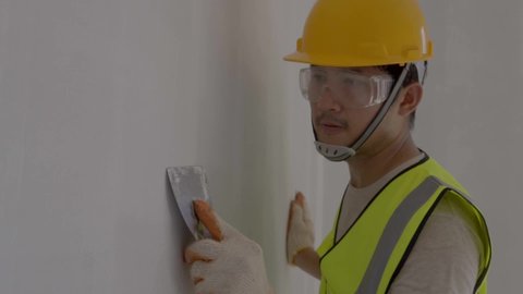 Asian construction worker,spatula in hand against the background of a white wall, work plasterer. Putty walls with their own hands.